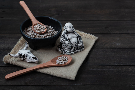 sunflower seeds on black plate and stone figureの写真素材