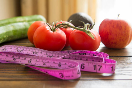Vegetables - zucchini, tomatoes and an apple with measuring tapeの写真素材