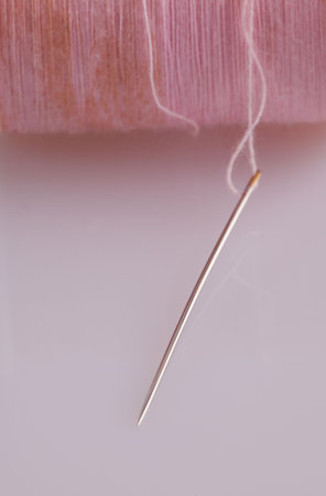 Needle attached to an old pink role of thread.
