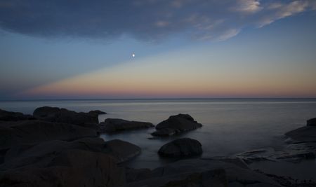 Moon over a lake shore at sunset looking over Lake Superior from Minnesota to Wisconsin.の写真素材