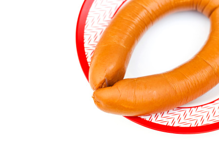 Appetizing sausage on a plate with a red border on a white backgroundの写真素材