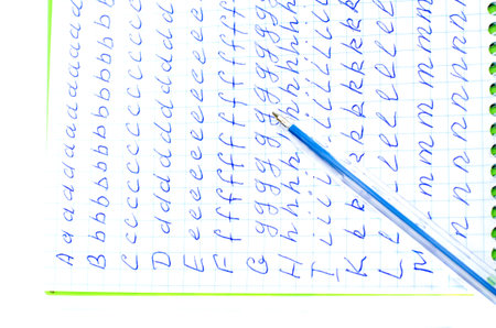 Alphabet in notebook into a cell. On top is the blue pen. On a white background. Isolate.