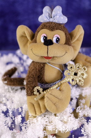 Christmas monkey with a bow. With the key in the legs on a blue background.の写真素材