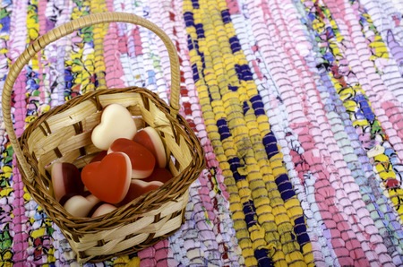 Basket with sweets in form of heart on multi-colored matting.の写真素材