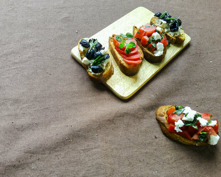 Sandwiches with tomatoes, olives and cheese on a wooden board.の素材