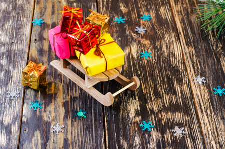 Christmas sleigh with gifts are on a dark background. Nearby lie gift, snowflakes and fir branch.の写真素材