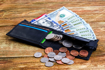 Different coins in wallet, american flag and banknotes hundred  dollars. On a wooden surface.の写真素材