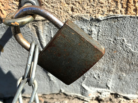 The old lock fastens the chain to the ring in the wall. Close-up.の写真素材