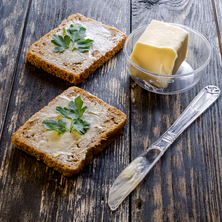 Homemade dietetic tasty sandwiches with butter and parsley for breakfast. On dark rustic wooden background. Square. Close-up.の写真素材