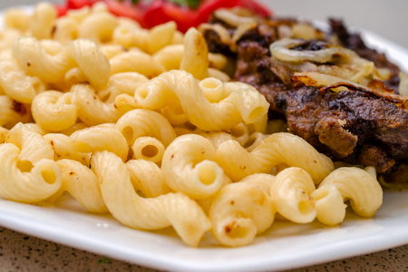 Cooked on homemade pasta with fried pork or beef meat, and white sauce, lie on a white dish. The concept of homemade appetizing food.の写真素材