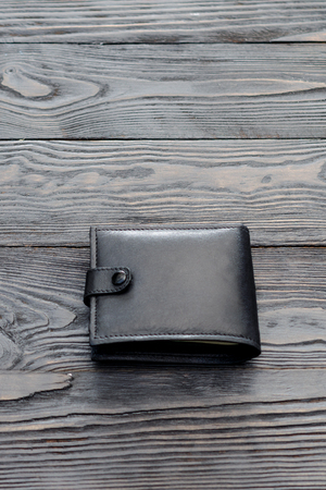 Black leather elegance men's wallet on dark wooden background. Vertical. Single object.の写真素材