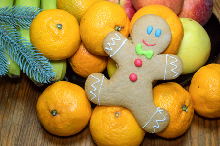 Christmas homemade gingerbread in the form of a little man on a wooden table among tropical fruits....