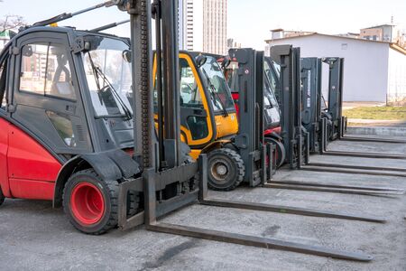 Several cargo loaders are lined up in an open construction site. Outdoors.のeditorial素材