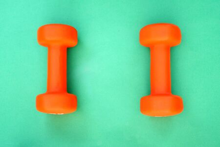 Doing sports. Two orange dumbbells lie on a green surface.の写真素材
