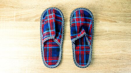 A pair of colorful comfortable, cushioned, checkered disposable slippers are on the wooden floor. Close-up. Indoors.の写真素材
