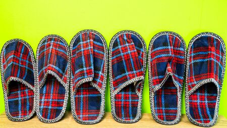 A lot of  of colorful comfortable, cushioned, checkered disposable slippers leaned against yellow wall. Close-up. Indoors.の写真素材
