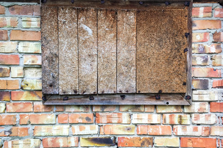 Boarded up window in abandoned old brick wall in barn or closed old house. Close-up. Outdoors.