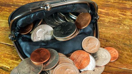 Open black leather pocket wallet full of various coins. Financial crisis, poverty, lack of money. On wooden background or table. Close-up.の写真素材
