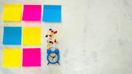 Several blank colorful   notes with copy space for text on light background. Blue alarm clock, push pins. Concept prepare for teamwork or brainstorming. Top view. Flat lay. Close-up. Indoors.の写真素材