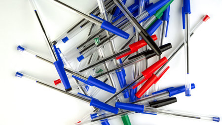 Pile of a lot multi colored plastic ballpoint pens on white background. Abstract stationery...