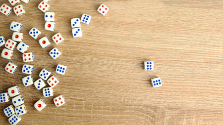 Many white dice with red and blue dots on wooden table. Casino gambling concept. Close-up. Indoors.