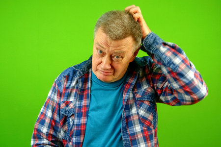 Confused puzzled, bewildered senior caucasian man in checkered shirt expression and scratching his...