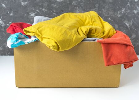 Summer clothes in a cardboard box. Seasonal clothing for shipping or donation. Close up view.の写真素材