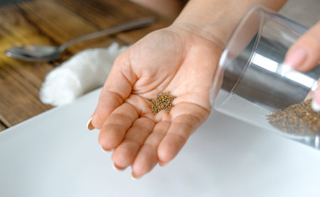 Home gardening. Woman poured arugula seeds from a glass into her palm. Preparation for planting...