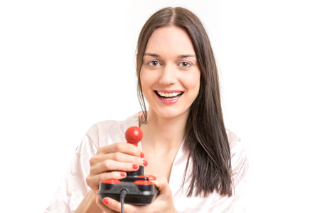Attractive young brunette woman wearing a pink nightgown, laughing while operating a joystick. Royalty free stock photo.の写真素材