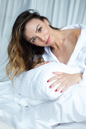 Girl in bed hugging a pillow, flirtingの写真素材