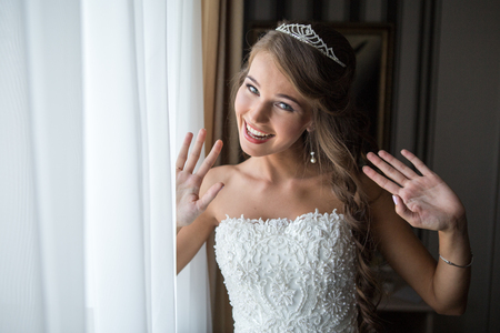 happy bride poses for a photograph in the bedroom by the window before the weddingの写真素材