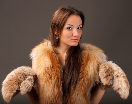 portrait of a young woman with a fur vest mittensの写真素材