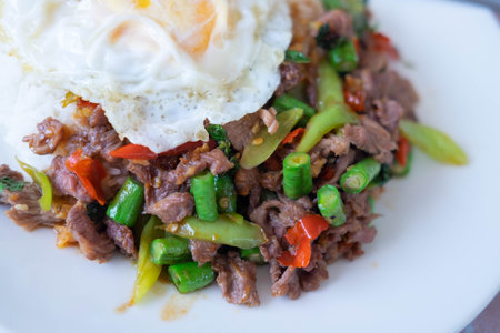 Stir-fried pork with basil and fried egg on white dishの写真素材