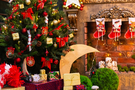 Christmas green fir-tree decorated with toys and a fireplaceの写真素材
