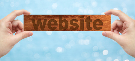 The Hands holding a wood engrave with word website with bokeh backgroundの写真素材