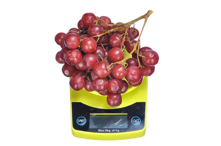 measure delicious bunch red seedless crimson grape on electronic kitchen scale isolated on white.