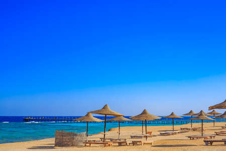 Wonderful sunset view of the beach on the shore of the tropical sea with sun umbrellas.の写真素材