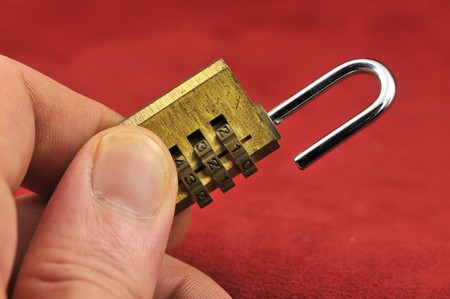 Brass yellow gold combination lock on a red backgroundの写真素材
