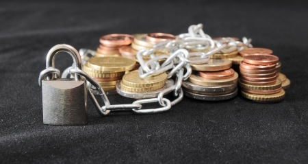 Secure Savings - a Lock and Some Coins on a Black Backgroundの写真素材