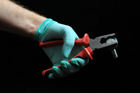 Pliers and a Hand on a Black Background