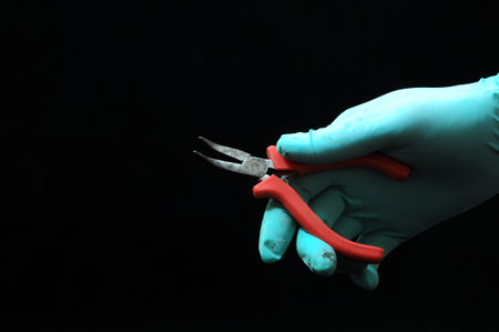 Pliers and a Hand on a Black 