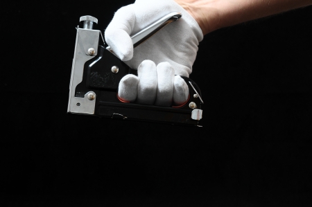 Stapler Pliers and a Hand on Black Backgroundの写真素材