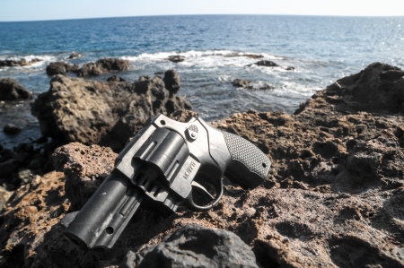 Plastic Revolver Gun Toy on the Volcanic Rocksの写真素材