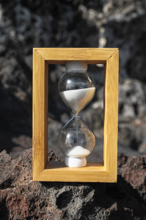 Time Concept White Sand Hourglass on the Volcanic Rocks