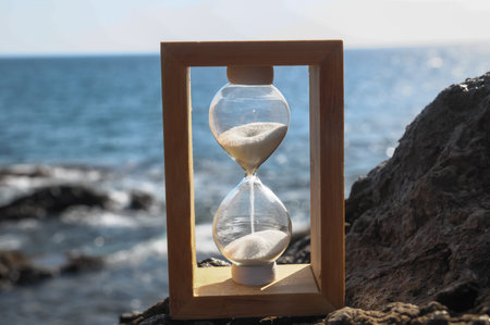 Time Concept White Sand Hourglass on the Volcanic Rocks