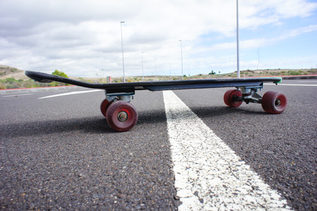 Vintage Style Longboard Black Skateboard on an Empty Asphalt Desert Roadの写真素材