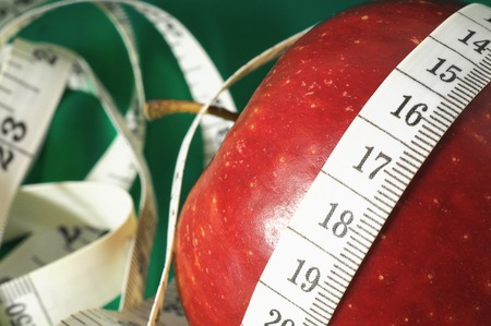 Measuring Tape Wrapped Around Red Apple as a Symbol of Dietの写真素材
