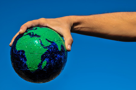 Vintage Old Globe Earth and Human Hand over a Blue Skyの写真素材