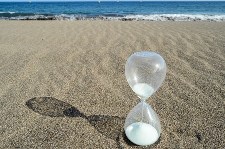 One Hourglass on the Sand Beach Near the Ocean Time Conceptの写真素材