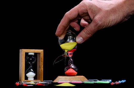 Deadline Concept Broken Hourglass with Yellow Sand on Black Background